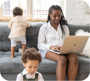 A parent works at a computer while their children play around them.